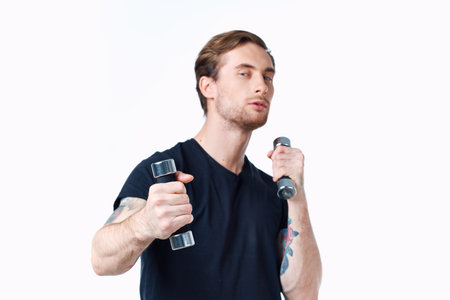 sporty man in a black t-shirt with dumbbells in his hands on a white background