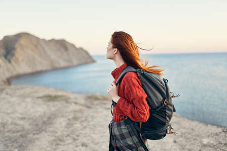 beautiful woman with a backpack in the mountains red sweater model hairstyle ocean seaの写真素材