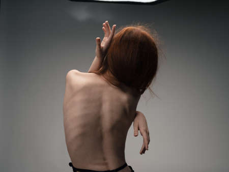 Nude woman touches herself with hands on a light background model cropped viewの写真素材