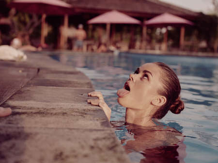 cheerful woman in the pool shows tongue rest nature tropicsの写真素材