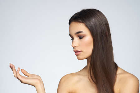 Woman with long hair bared shoulders clean skin body care light backgroundの写真素材