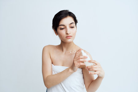 Pretty brunette with bare shoulders lotion in hands skin careの写真素材