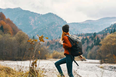 woman in a jeans sweater with a backpack rest in the mountains near the river in natureの写真素材