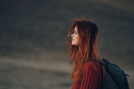 beautiful woman gesturing with her hands on nature in the mountains red sweater backpack travelの写真素材
