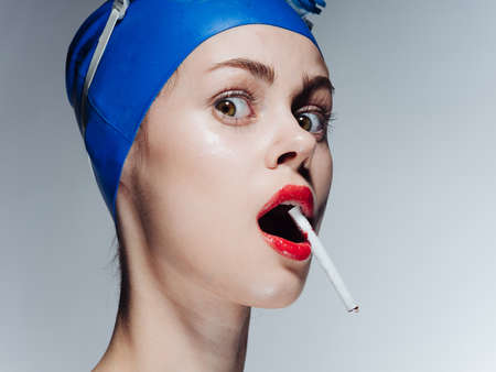 Woman swimmer in a blue swimming cap and glasses with a cigarette in her teethの写真素材