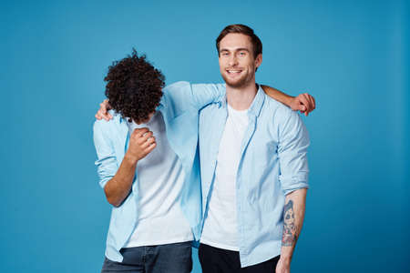young men in identical shirts hugging on a blue background best friends funの写真素材