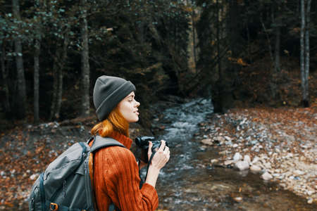 woman with a camera near a pond in the mountains on nature and trees