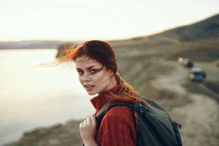 portrait of woman with backpack on nature in the mountains near the sea at sunset cropped viewの写真素材