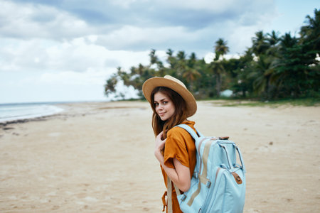 woman with a backpack walks on the beach near the sea and tall trees Summer sunの写真素材