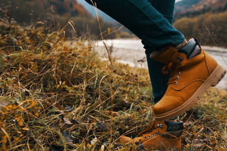 womens feet jeans shoes dry grass autumn river mountains in the distanceの写真素材