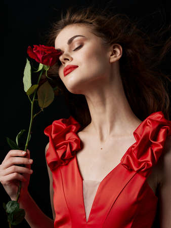 a woman in a dress holds a red rose in her hand and makeup on her face Valentines Day March 8