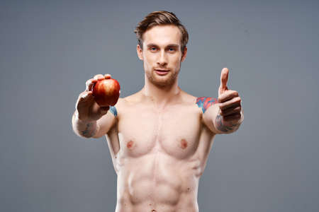 athletic guy with a pumped up torso healthy lifestyle nutrition vitamins red appleの写真素材