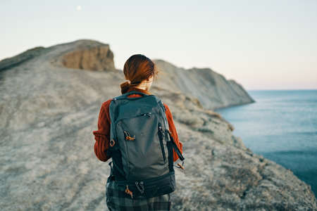 beautiful woman hiker with a backpack on her back in the mountains near the sea landscape modelの写真素材