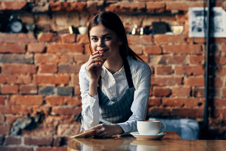 woman waiter in cafe uniform near the tableの写真素材