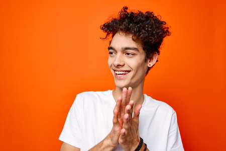 guy in a white t-shirt gesturing with his hand on an orange background