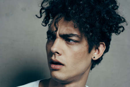 portrait of a handsome guy with curly hair on a gray background white t-shirt close-up modelの写真素材