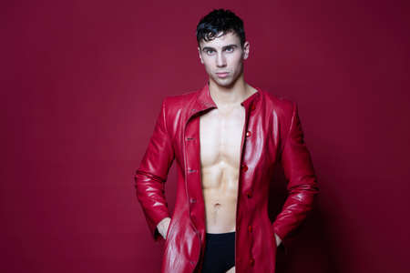 male athlete brunette in a leather coat on a red backgroundの写真素材