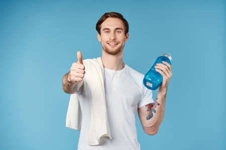 sporty man with tattoos on his arms drink bottle energy workout blue backgroundの写真素材