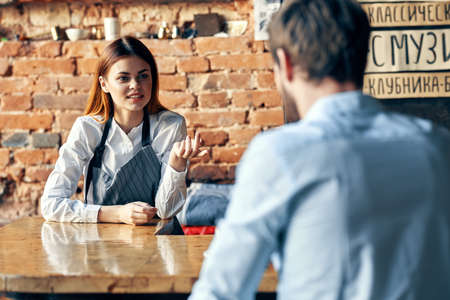 female waiter brings coffee to customer of service cafeの写真素材