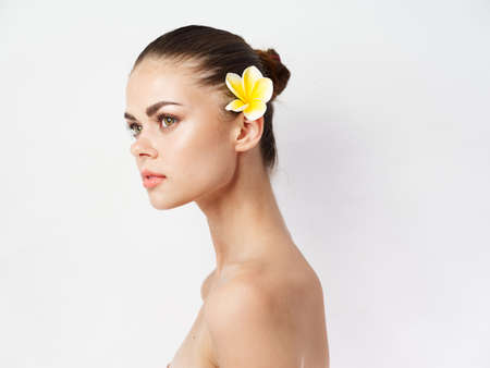 pretty woman with bare shoulders yellow flower behind ear clear skin charm