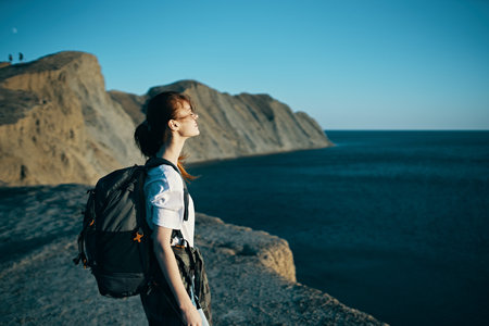 woman with backpack travels in the mountains near the sea
