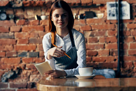 woman waiter coffee cup Near the table brick wallの写真素材