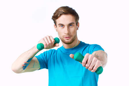 man in blue t-shirt from dumbbells in hands fitness