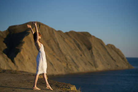 a traveler in a white dress walks in nature in the mountains near the seaの写真素材