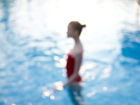 woman in red swimsuit stands in the pool transparent water model side viewの写真素材