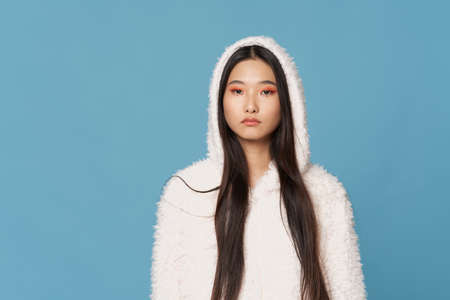 woman of asian appearance in white sweater with a hood winter clothing