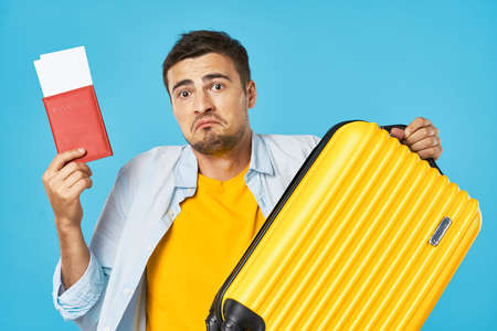 man with suitcase passport and plane tickets blue backgroundの写真素材