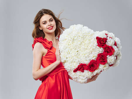 a woman in a red dress holding a heart of decorative flowers gifts March 8 Valentines Dayの写真素材