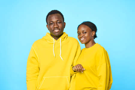 cheerful man and woman of african appearance in yellow sweaters fashion studio blue background