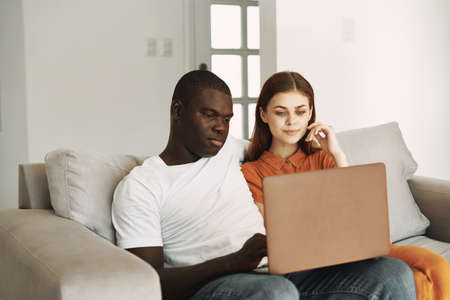 young couple at home on the couch in front of a laptop vacation internet