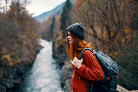 woman hiker in the autumn forest on the bridge near the river travelの写真素材