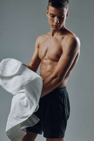 man with a towel in his hands pumped up body black shorts gym exerciseの写真素材