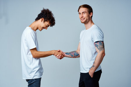two friends hold hands in white t-shirts isolated backgroundの写真素材