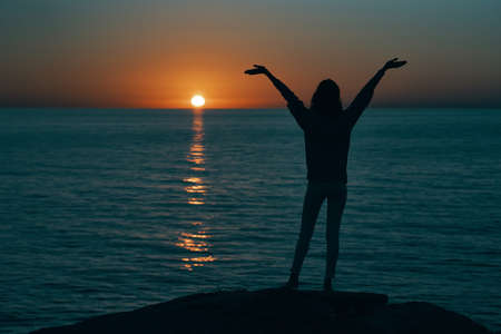 female silhouette gesturing with hands sunset sea modelの写真素材