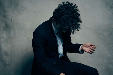 Cheerful curly-haired guy in a suit fashion business officialの写真素材