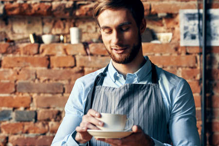 man in apron barista work professional a cup of coffee in handの写真素材