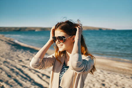 woman in sweater and sunglasses on the beach near the sea in the mountainsの写真素材