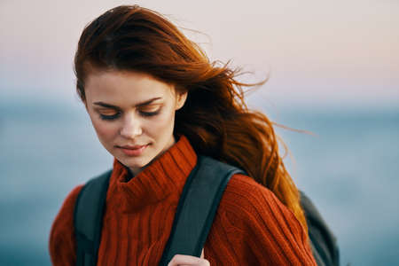 woman woman hiker with a backpack near the sea in the mountains in nature and a red sweater model
