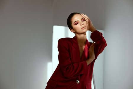 sexy woman in red jacket touches her face on dark backgroundの写真素材