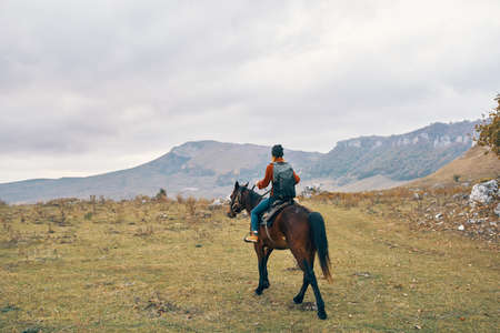 woman hiker with backpack riding horse landscape mountains fresh airの写真素材