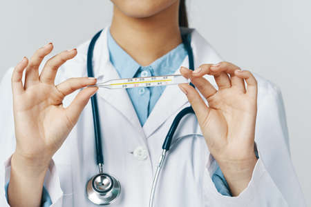 woman doctor with a thermometer in her hands and a stethoscope around her neck