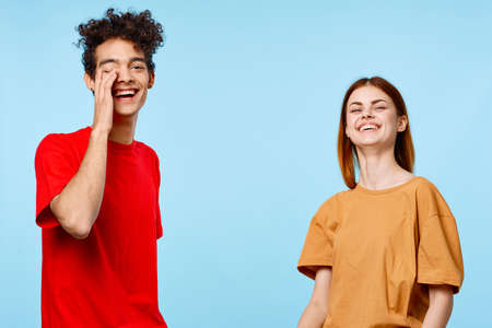 cheerful young couple in multicolored t-shirts communication studio blue background