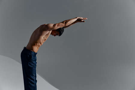 bodybuilder Fitness man with a pumped-up torso and with raised arms leaned forward side view