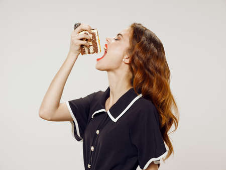 woman with cake near face and curly hair black dress holidays birthdayの写真素材