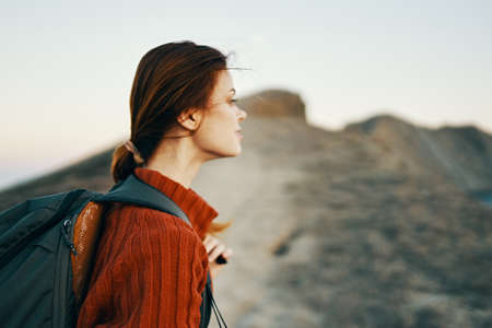 woman climbs the mountains along the path and a backpack on her back side viewの写真素材
