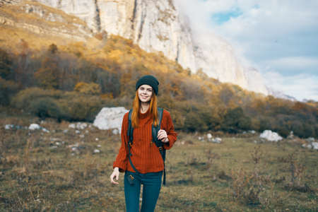 woman in a warm hat with a backpack on her back and in a sweater outdoors in the mountains gesticulate with her handsの写真素材